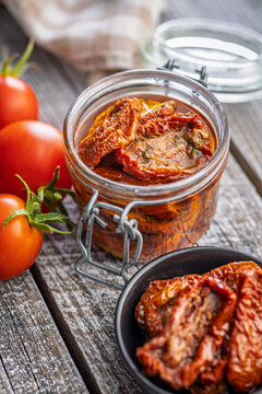 Jar of Sun-Dried Tomatoes in Olive Oil on Rustic Wooden Table with Fresh Tomatoes