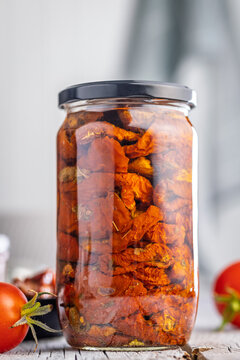 Jar of Sun-Dried Tomatoes in Oil on Rustic Wooden Table With Bowl and Fresh Tomatoes