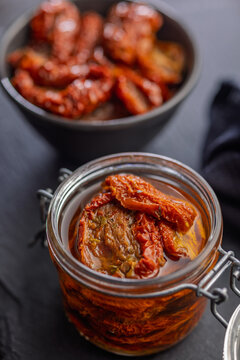 Sun-Dried Tomatoes in Jar with Olive Oil on Slate Board, Rustic Preserved Tomato Close-Up