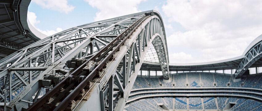 Close-up view of steel retractable roof arch over modern empty stadium seating and structural mechanism