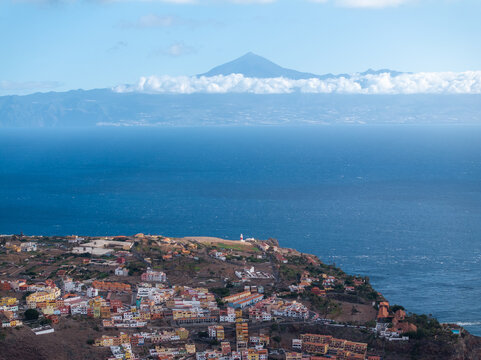 Aerial view of the coastal town of La Palma with its lighthouse and colorful buildings, set against the Atlantic Ocean and the distant volcanic peak of Mount Teide, Canary Islands, Spain.