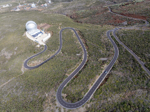 Aerial view of the winding road leading to the Gran Telescopio Canarias observatory dome set within the rugged volcanic landscape of La Palma, Canary Islands, Spain.