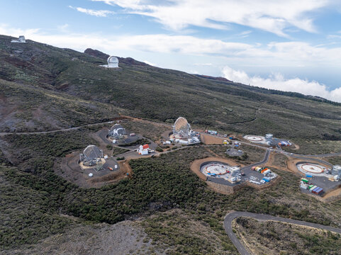 Aerial view of the Roque de los Muchachos Observatory on La Palma, featuring large telescope domes and arrays set against the rugged volcanic landscape of the Canary Islands, Spain.