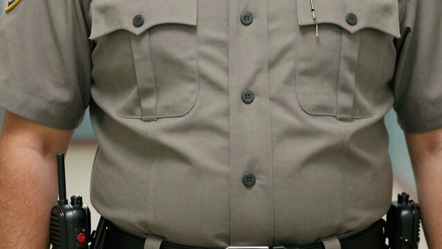 Close view of prison correctional officer in gray uniform with duty radio equipment