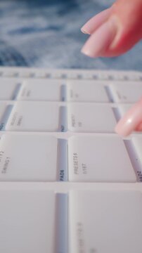 A woman with manicured nails taps rhythmic beats on white midi controller drum pads outdoors. Extreme macro close-up highlights tactile equipment buttons during a bright music session.