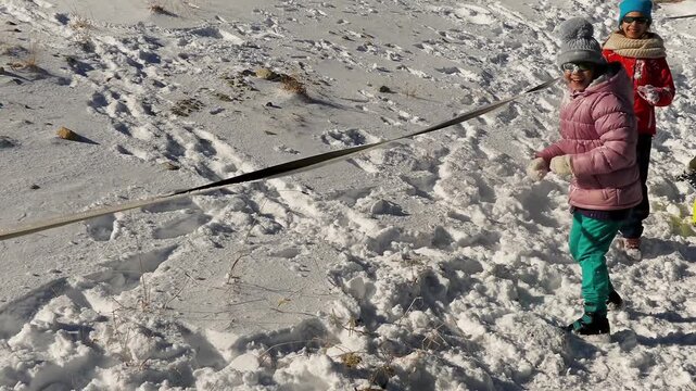 Two little girls play snowballs on the snowy mountain slopes.