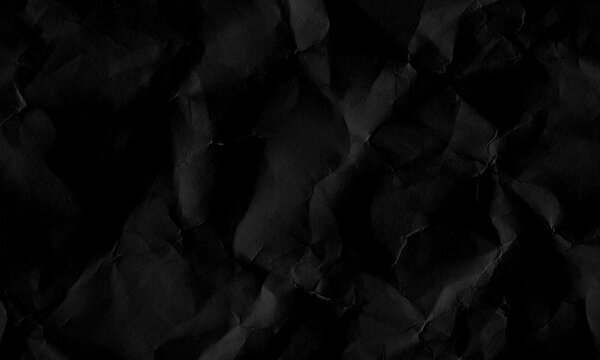 Dark black crumpled paper texture background with creased surface pattern and dramatic shadows Background