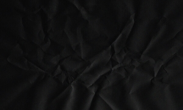 Dark black crumpled paper texture background with creased surface pattern and abstract shadows Background