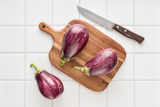Three fresh purple eggplants  on wooden cutting board