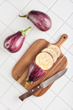 Three fresh purple eggplants  on wooden cutting board