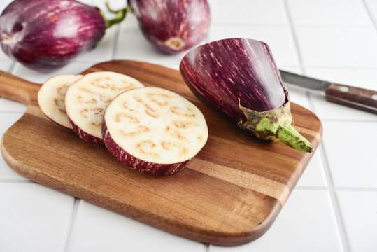 Three fresh purple eggplants  on wooden cutting board