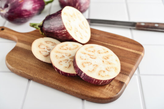 Three fresh purple eggplants  on wooden cutting board