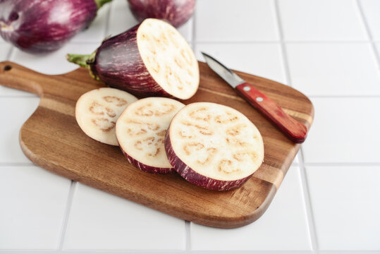 Three fresh purple eggplants  on wooden cutting board