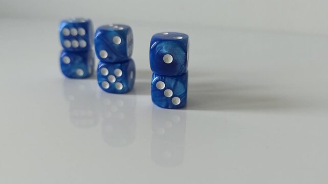Short video showing groups of stacked blue dice on a reflective white surface from different viewing angles. Concept of balance, probability, risk, strategy, uncertainty, chance and calculated decisio