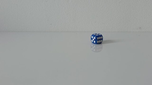 Blue dice rolling across a clean white surface and coming to a stop, with generous copy space. Concept of chance, probability, luck, uncertainty, risk and random outcome.