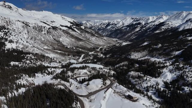 Winding Mountain Road Cutting Through Snowy San Juan Mountains and Pine Forest in Colorado aerial drone 4k video