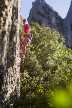 Young woman rock climbing a steep rock face