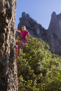 Young woman enjoying challenging rock climbing in mountains
