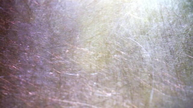 Scratched metal texture background with light leaks. Close up of metallic surface with fine scratches, lens flare and abstract pattern.