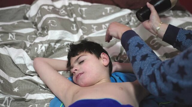 Mother drying hair of son with cerebral palsy