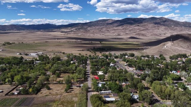 Summer aerial of residential townscape and arid foothills in Saguache Colorado with dense housing development and mature trees lining the streets