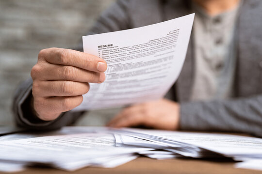 Recruiter Reviews Resumes to Select Best Candidates for Upcoming Interviews in an Office Setting