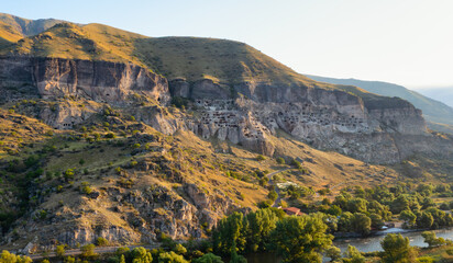 Aerial view of Vardzia cave monastery carved into the cliffs of southern Georgia at golden hour © Игорь Кляхин