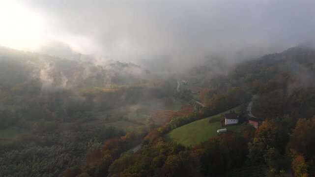 Aerial view of mountain forests shrouded in morning mist with dramatic sunbeams breaking through the clouds	