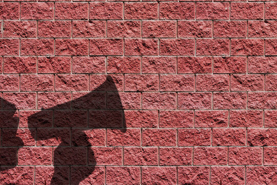 megaphone speaking announcing man shadow against red brick wall background or wallpaper