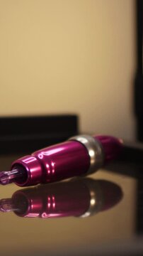 Hand in black glove picking up pink permanent makeup tattoo machine close up