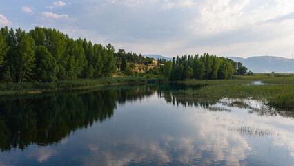 Obraz premium A soothing natural landscape where the trees and the sky are reflected on the calm surface of the lake.