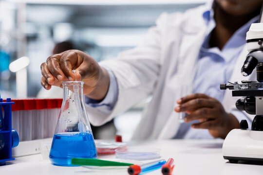 Close-up laboratory specialist pipetting agent into blue test tube