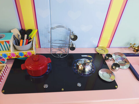 Colorful pretend play kitchen with toy cookware utensils teapot saucepan metal dishes creating interactive educational environment for children encouraging imagination role playing 