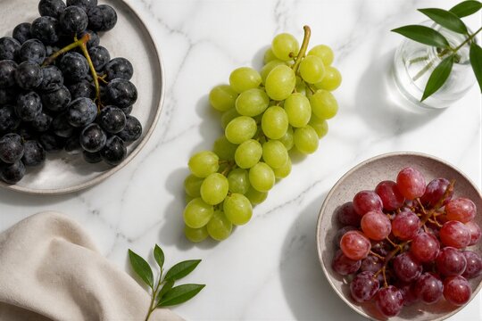 Mixed grapes arranged on marble countertop with plates
