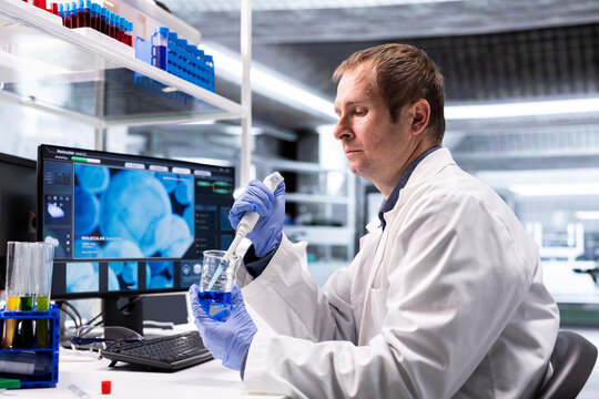 Chemistry scientist works in a biolab with a pipette and jar, preparing a chemical mixture during a laboratory procedure focused on molecular biology, bioengineering and medical research.