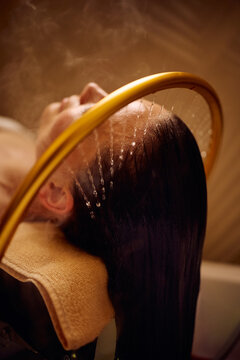 Close up of woman enjoying soothing hair rinse at wellness spa.