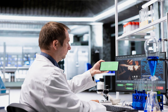 Lab expert conducts an experiment with tools and a chroma key phone screen, supporting biotechnology, bioengineering and healthcare research for future medical applications and innovation.