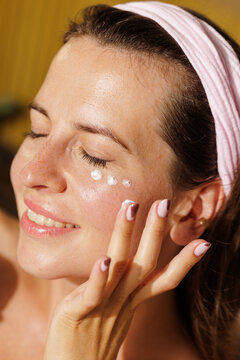 Woman Applying Moisturizing Eye Cream During Home Skincare Routine