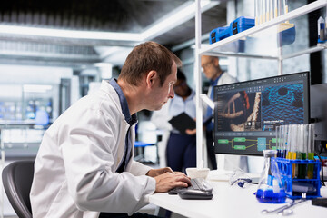 Chemist in a biolab studies experiment data on a computer with fascination and curiosity, reading...