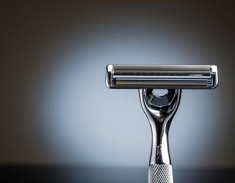 a shiny metal safety razor on a plain background