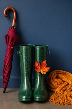 Green rain boots with red umbrella and autumn scarf