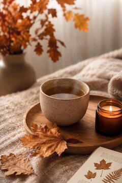 Cozy autumn tea with candle and fallen leaves