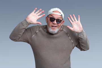 Naklejka premium Excited senior man raises open hands in a cheerful greeting on gray background