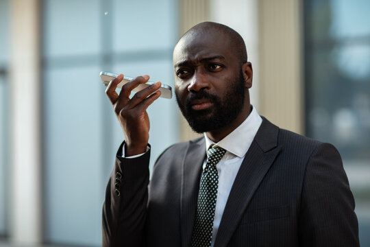 Businessman using voice command on smartphone outside office