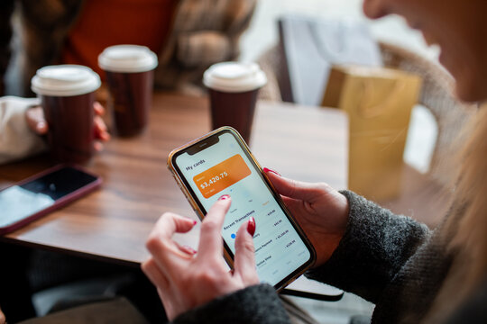 Close-up of woman using mobile banking app in coffee shop