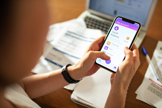 Woman checking mobile banking app at home desk