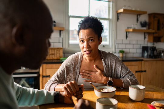 Concerned woman talking with partner at kitchen table