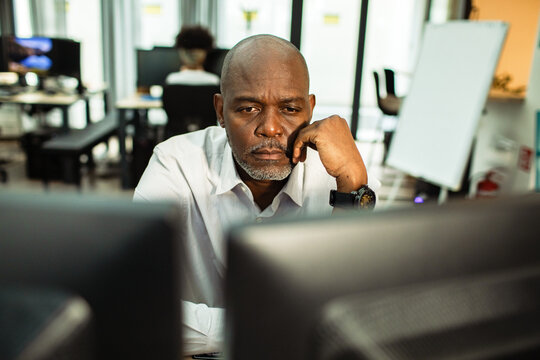 Focused mature man working at computer in modern office