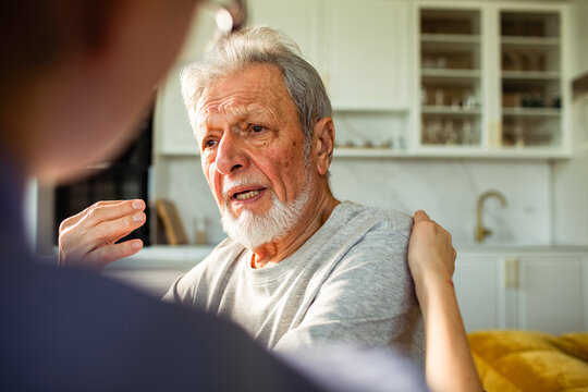 Senior man comforted by caregiver in home kitchen