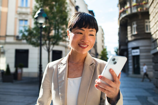 Smiling businesswoman using smartphone on city street